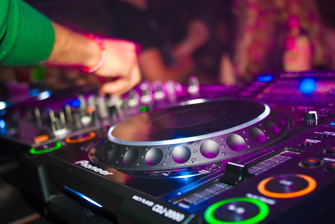 Close-up of a DJs hands on mixing console at a vibrant party in Utrecht.