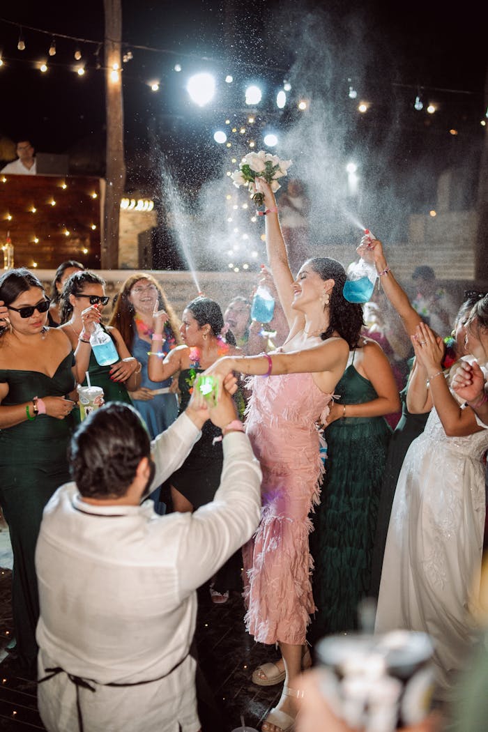 Lively wedding party with guests celebrating under string lights at night.
